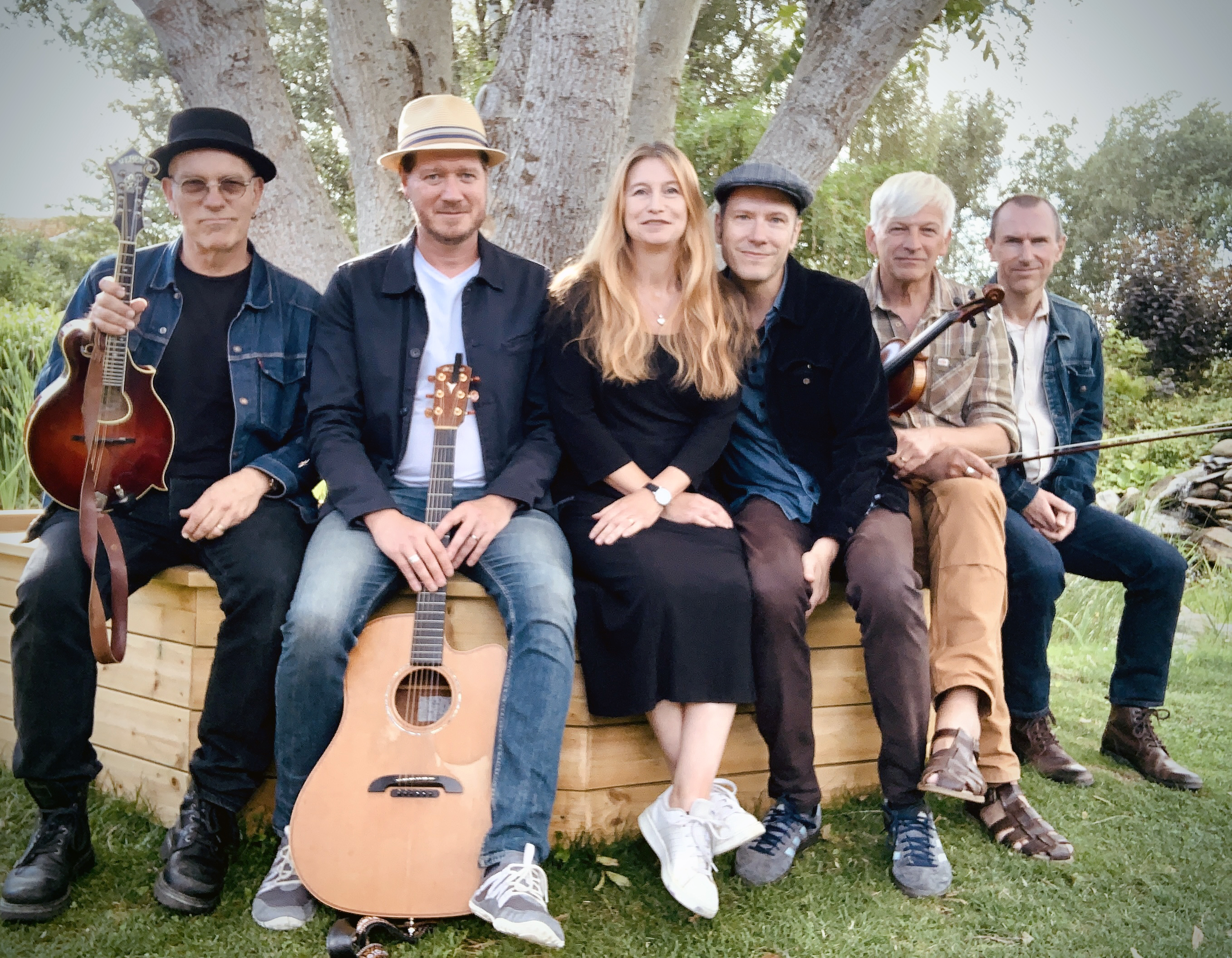 Hela West of Eden sitter sommarklädda på en bänk vid ett träd